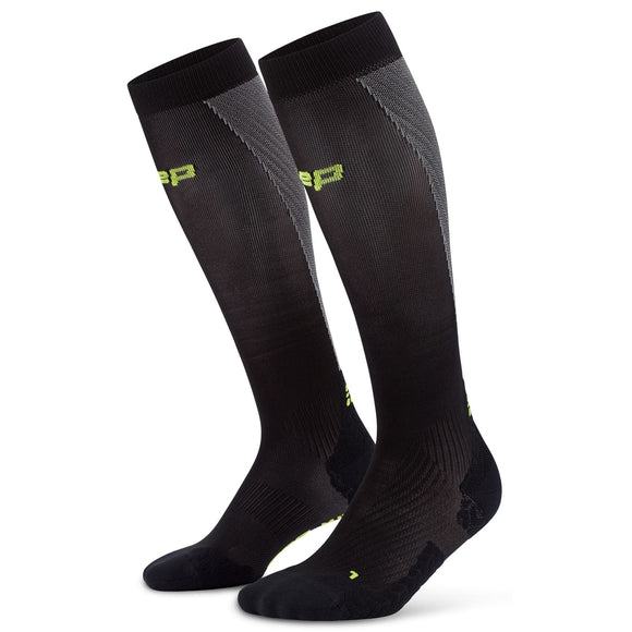 Et par CEP Core Run Ultralight Compression Socks til kvinder i sort/grå med gult branding på siden og i toppen står oprejst mod en hvid baggrund.