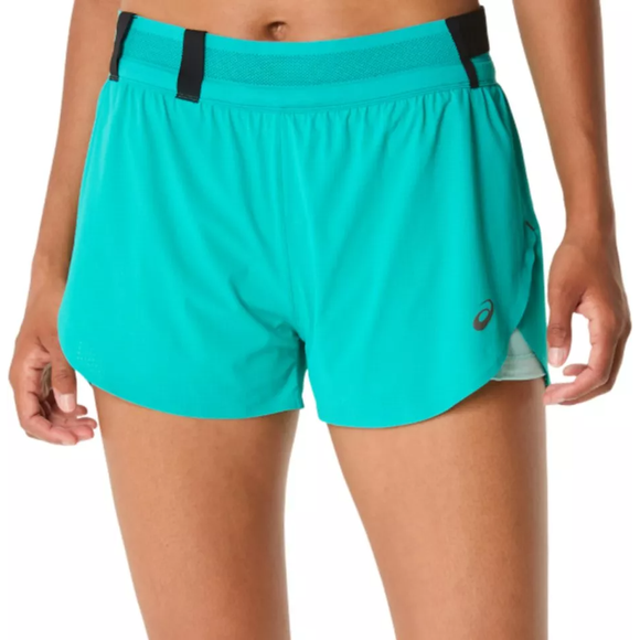 En person iført Asics Metarun Split Short Dame i Wave Teal med sort linning og lille logo på venstre ben står på en almindelig baggrund, hvor kun underkroppen og overbenene er synlige.