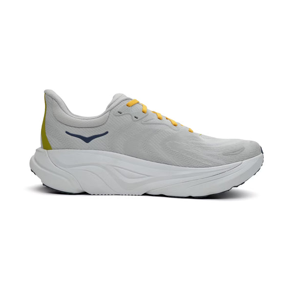 Hoka Arahi 8 herre løbesko i Stardust/Cosmic Grey har en hvid og grå farve med kraftig, skulptureret sål samt mørkeblåt Hoka-logo på siden. Skoen præsenteres på en ensfarvet hvid baggrund.