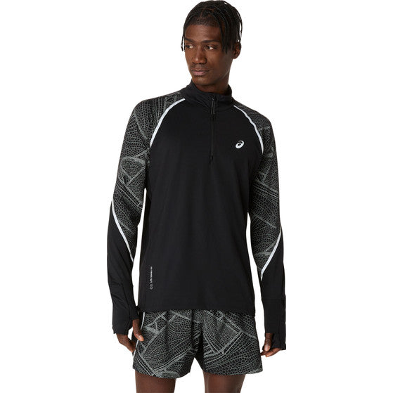 En mand iført en sort og mønstret Asics Limited Series Lite-Show Ls Top, Herre, Performance Black med reflekterende detaljer og matchende mønstrede shorts står på en almindelig hvid baggrund.