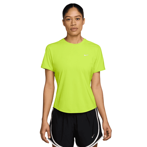 En kvinde kigger fremad i en neongul Nike Swift SS Running Top, Dame, Cyber/Reflective Silv med Dri-FIT-teknologi og sorte Nike-atletikshorts med hvid kant og reflekterende detaljer på en almindelig hvid baggrund.