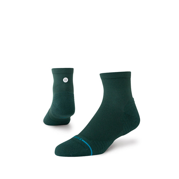 Et par Stance Run Light QTR løbestrømper, unisex i fyrretræ, er vist på en hvid baggrund. Den ene sok står oprejst, den anden er vinklet, så man kan se siden og toppen. Et lille hvidt cirkulært logo vises på oversiden.