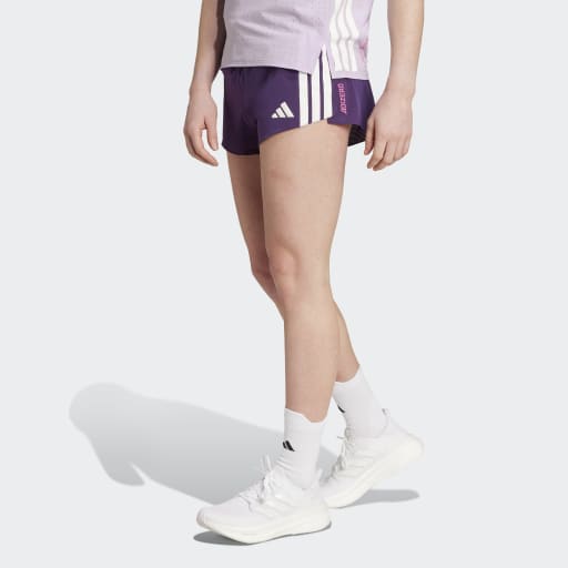 En person i en Adidas Adizero Gel-top (lyslilla), Dame-shorts (mørklilla), hvide Aurplu-sokker og hvide sportssko står på en almindelig hvid baggrund. Personens hoved er ikke synligt.