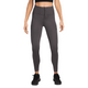 En person i en sort crop top, Nike Trail 7/8 Tights til kvinder i Thunder Grey/Black med sidelommer og sorte sportssko står på en almindelig hvid baggrund. De højtaljede tights er i Dri-FIT-materiale. Personens ansigt er ikke synligt.