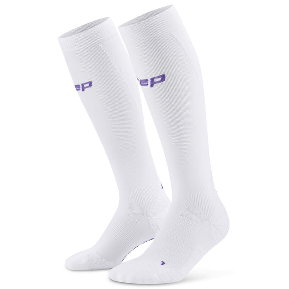 Et par CEP Core Run Ultralight Compression Socks til kvinder i hvid med struktureret fod og lilla CEP-mærke øverst, vist lodret mod en almindelig hvid baggrund.