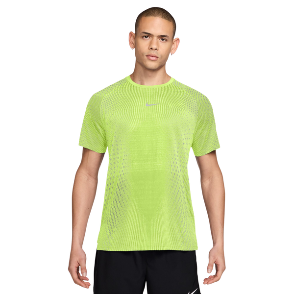 En mand har en Nike Stride Aero-FIT kortærmet løbetrøje på i farven Lt Lemon Twist/Reflective Silver, der har et mønstret, reflekterende overfladebehandling.