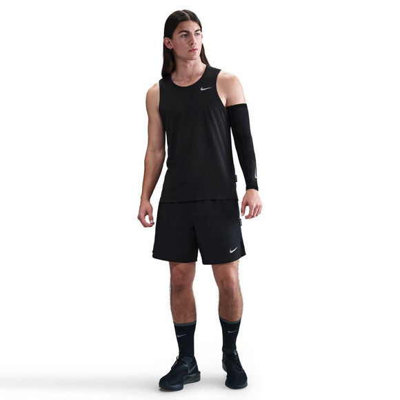 En person med langt hår står lidt til siden iført en sort/reflekterende sølv Nike Dri-Fit Running Tank Top (Herre); baggrunden er almindelig hvid.