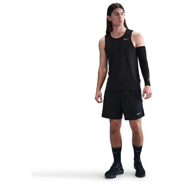 En person med langt hår står lidt til siden iført en sort/reflekterende sølv Nike Dri-Fit Running Tank Top (Herre); baggrunden er almindelig hvid.