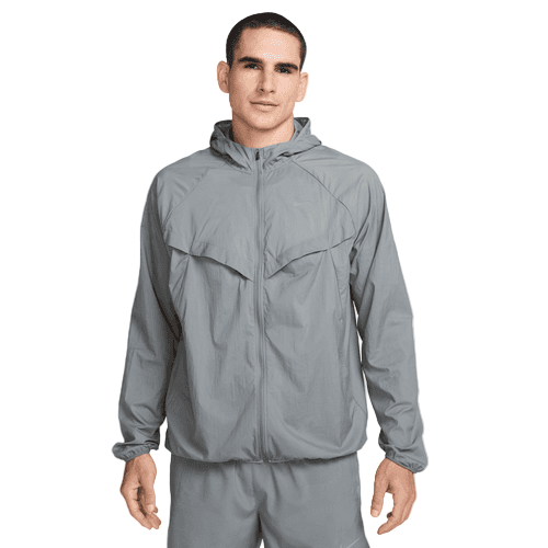 En mand med kort mørkt hår og et neutralt udtryk ser frem for sig iført en Nike Repel UV Running Jacket, Herre, i Smoke Grey/Smoke Grey/Reflective Silv, med lynlås foran, vinklede brystklapper og elastiske manchetter.