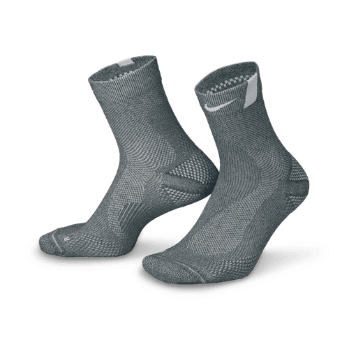 Et par Nike Fast Lightweight Ankle unisex-strømper i Dk Smoke Grey/Pure Platinum/White med ribbede manchetter, hvide detaljer, strukturerede mønstre og Dri-FIT-teknologi vises stående på en hvid baggrund.