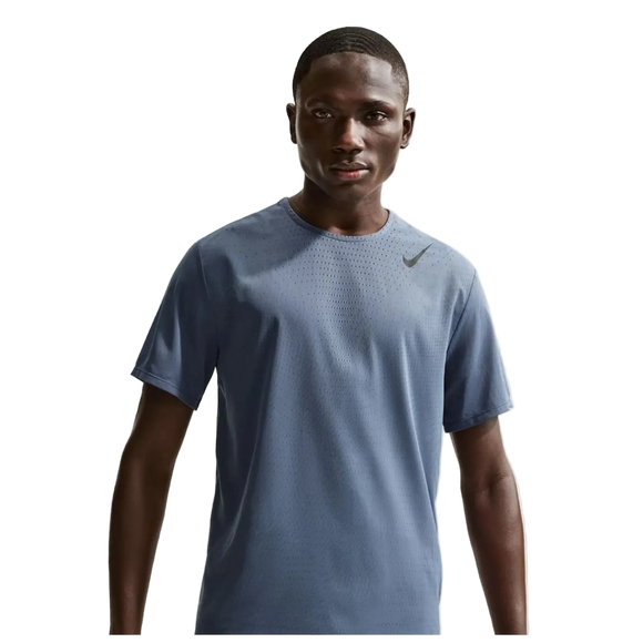 En mand står med ansigtet fremad i en blå Nike Dfadv Aroswft Ss Top, Herre, Diffused Blue/Black med et lille swoosh-logo på brystet mod en almindelig hvid baggrund.