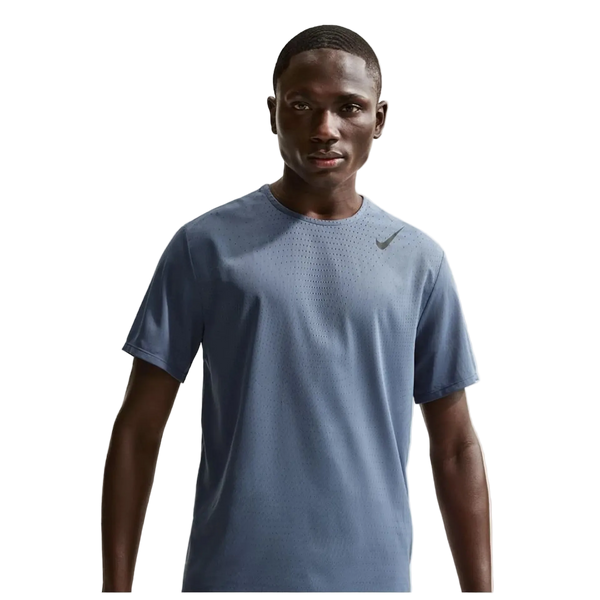 En mand står med ansigtet fremad i en blå Nike Dfadv Aroswft Ss Top, Herre, Diffused Blue/Black med et lille swoosh-logo på brystet mod en almindelig hvid baggrund.