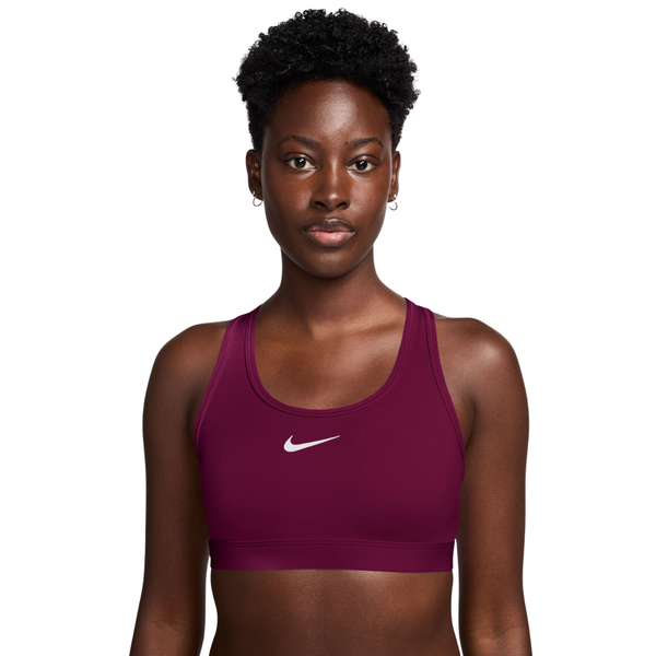 En person iført en Nike polstret sports-BH, Dame, True Berry/White, med et mørkt bærfarvet, polstret design og et hvidt Swoosh-logo.
