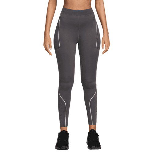 En person iført Nike Therma-FIT ADV High-Waisted 7/8 Reflective Running Leggings til kvinder i Thunder Grey/Dk Smoke Grey og sorte sportssko står på en hvid baggrund med armene afslappet ned langs siden.