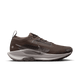 Nike Pegasus Trail 5 Gore-Tex Dame i Ironstone/College Grey-Velvet Brown har en overdel i mesh, sorte og grå detaljer, hvid "Nike Trail ATC"-mellemsål og trækflig i hælen. Denne vandtætte løbesko er perfekt som trailsko dame. Vist på en hvid baggrund.