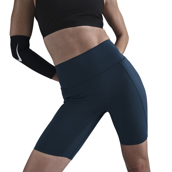 En person står med hænderne på hofterne iført Nike Medium-Support High-Waisted 8" Biker Shorts i Black/Anthracite/Dk Smoke Grey og en sort sportstop. Shortsene har InfinaSmooth Dri-FIT-teknologi.