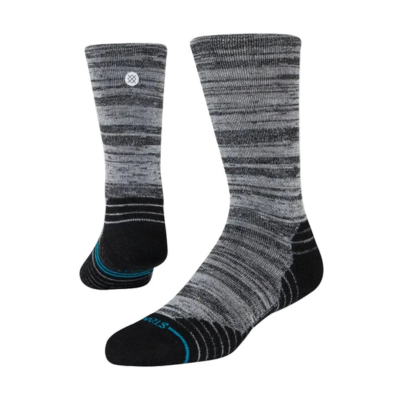 Stance Mid Wool Crew Unisex-strømper i sort med et gråt og sort marmoreret mønster med sorte hæle, tæer og såler samt et lille hvidt cirkulært logo i toppen. Vises på en almindelig hvid baggrund.