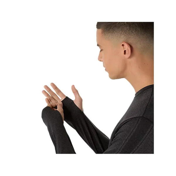 En mand bærer Asics Road Seamless Ls Top, Herre, Performance Black, og placerer sin venstre tommelfinger i ærmet med ansigtet vendt mod højre mod en almindelig hvid baggrund.