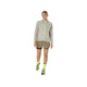 En person står på en hvid baggrund iført en lysegrå jakke med hætte og neongule detaljer, Asics Fujitrail 2-N-1 Shorts i Dame Pepper/Performance Black, neongule sokker og Performance Black/neongule sneakers.