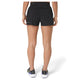 En kvinde står med ryggen til kameraet iført Asics Metarun Split Shorts, Dame, Performance Black og hvide løbesko med sorte og grønne detaljer. Baggrunden er helt hvid.