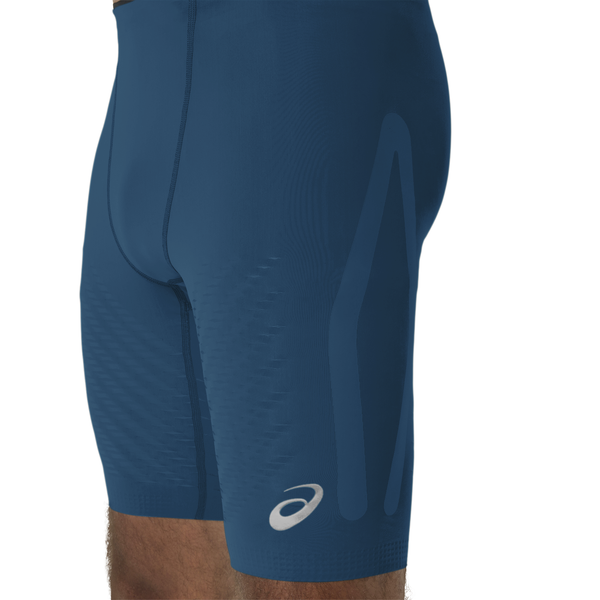 Nærbillede af en person, der bærer ASICS Metaspeed Tights, Herre, i farven Rich Navy med et diskret mønster og et hvidt logo nederst på venstre lår. Designet træder tydeligt frem mod den ensfarvede hvide baggrund.