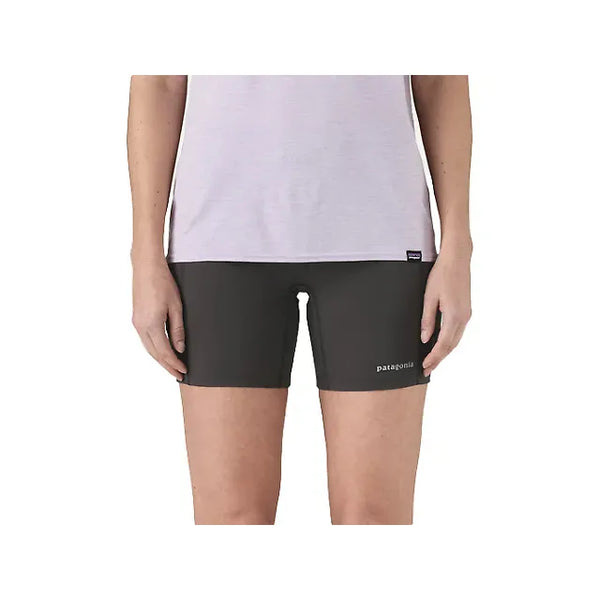 En person er iført en lyslilla skjorte og Patagonia Endless Run Shorts 6in, Dame, Black, vist fra overkrop til midt på låret mod en almindelig hvid baggrund.