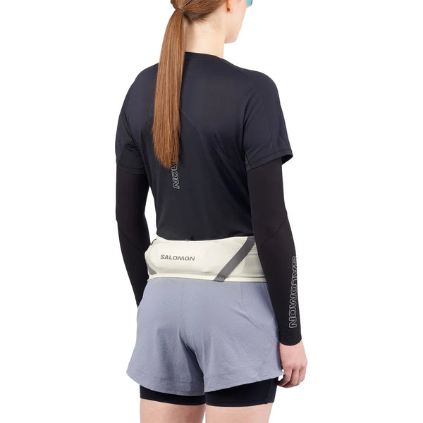 En person med langt hår i hestehale ses bagfra iført Salomon Pulse Belt, Unisex, Icicle/Castelrock-perfekt til løbetræning.
