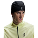 En person iført On Core Beanie i sort og en lysegul sportsjakke med lynlås og sort logo kigger ud til siden mod en hvid baggrund.