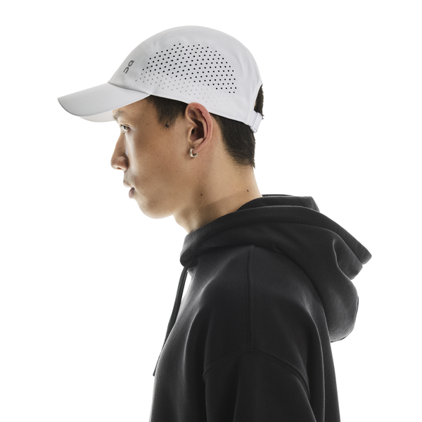 En mand iført On Lightweight Cap, Unisex, i hvid - ideel til løb og solbeskyttelse.
