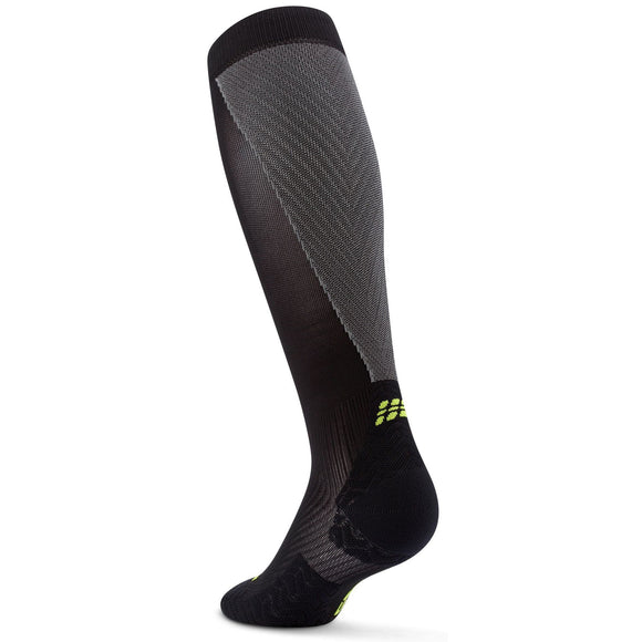 CEP Core Run Ultralight Compression Socks, Dame, Black/Grey er vist oprejst på en hvid baggrund; denne knæstrømpe har forstærket hæl og tå og et lille gult logo nær anklen.