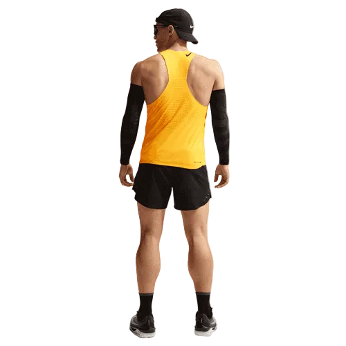 En mand kigger væk, iført sort kasket, solbriller, sorte ærmer, sorte shorts, strømper, løbesko og en Nike AeroSwift Running Singlet til mænd i Laser Orange/Black på en almindelig hvid baggrund.