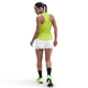 En kvinde med flettet hår kigger væk og er iført en Nike Dri-FIT Running Tank Top til kvinder i Cyber/Reflective Silver, hvide shorts, sorte knæstrømper og neongrønne sportssko på en almindelig hvid baggrund.