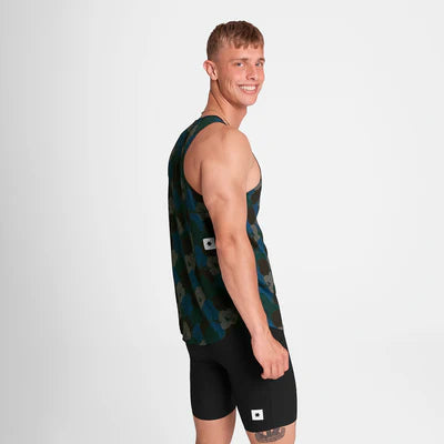 En mand smiler til kameraet i en Saysky Flower Combat Singlet, Herre, Blue Aop - en ultralet træningstop med camouflagemønster - sammen med sorte sportsshorts med små hvide firkantede lapper på en almindelig hvid baggrund.