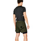 En mand står med ryggen til og er iført en mørk kortærmet skjorte og olivengrønne Saysky 2 in 1 Pace Shorts 5'' til mænd med en sort stjerne og SAYSKY-logoet bagpå på en almindelig hvid baggrund.