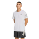 En person står på en hvid baggrund iført Adidas Adi365 Running Tee, Herre, White med grå ærmestriber og et lille logo på brystet, sammen med sorte shorts med hvide striber på venstre ben.