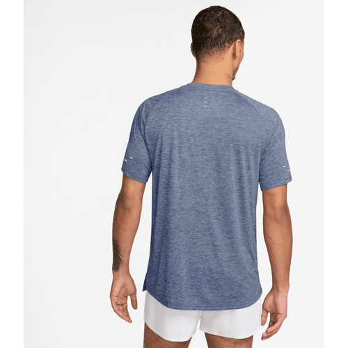 En mand står med ryggen til kameraet iført en Nike Dri-FIT ADV Short-Sleeve Running Top, Herre i World Indigo/Htr/Reflective Silv og hvide shorts på en almindelig hvid baggrund.
