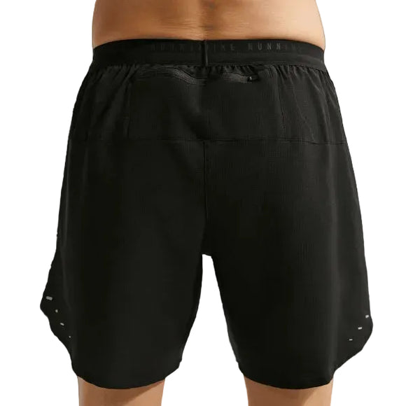 En person ses fra taljen og ned iført Nike Stride 7" Brief-Lined Running Shorts til mænd i Black/Reflective Silver med elastisk linning. Bagfra ses pasformen og længden på disse alsidige løbeshorts.