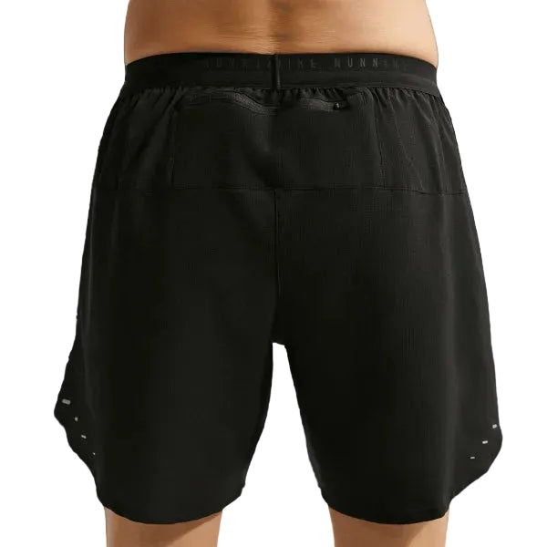 En person ses fra taljen og ned iført Nike Stride 7" Brief-Lined Running Shorts til mænd i Black/Reflective Silver med elastisk linning. Bagfra ses pasformen og længden på disse alsidige løbeshorts.