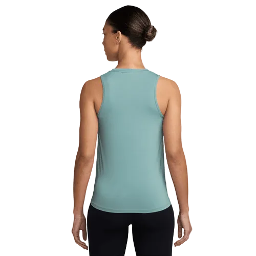 En person vender ansigtet væk fra kameraet iført en Nike Dri-FIT Classic Tank Top til kvinder i Cannon/White og sorte leggings. Håret er sat op i en pæn knold på en almindelig hvid baggrund.