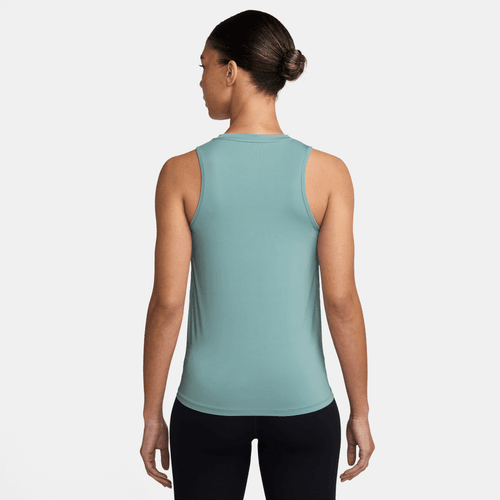 En person vender ansigtet væk fra kameraet iført en Nike Dri-FIT Classic Tank Top til kvinder i Cannon/White og sorte leggings. Håret er sat op i en pæn knold på en almindelig hvid baggrund.