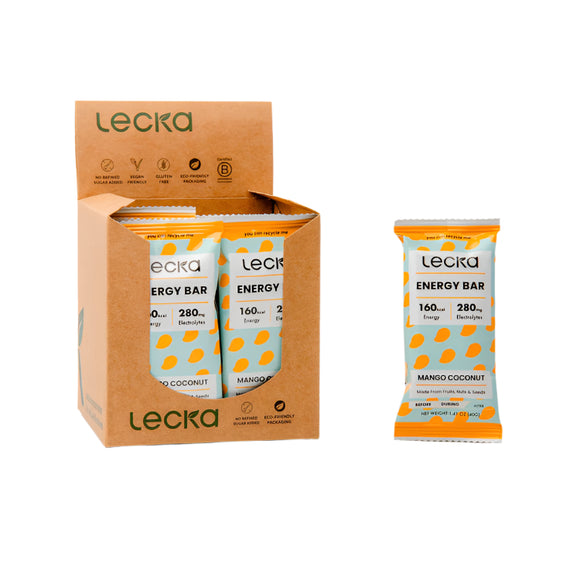 En brun Lecka-æske indeholder flere hvide og orange Mango/Coconut Energy Bars; en Lecka Energy Bar med Mango/Coconut-smag er udstillet separat ved siden af æsken.