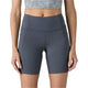 En person vises fra taljen til midt på låret iført Patagonia W's Maipo Shorts - 8 in., Dame, i Smolder Blue, sammen med en cropped mønstret top; de står med armene afslappet langs siden.