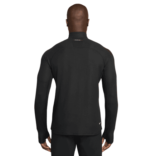 En person kigger væk fra kameraet iført en Nike ACG Half-Zip Running Top til mænd i Black/Black/Summit White og sorte bukser på en hvid baggrund.