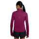 En mørkrosa Nike Swift Half Zip-løbetrøje til kvinder i farven True Berry/Reflective Silver med reflekterende detaljer på ryggen, båret over sorte sportsshorts.