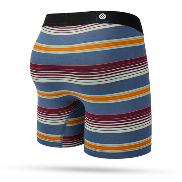 Stance Serape Boxer Brief, Herre, Jade har slim-fit vandrette striber i blå, rødbrun, gul og hvid med en sort linning og et centreret cirkulært logo. Vist mod en hvid baggrund.