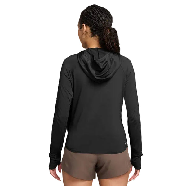 En kvinde med flettet hår bærer en Nike ACG Hooded Mid-Layer Running Top til kvinder i Black/Black/Summit White og brune shorts, mens hun står med ryggen til kameraet på en almindelig hvid baggrund.