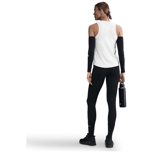 En kvinde i Nike Dri-FIT Classic Tank Top, Dame, White/Black, sorte leggings, ærmer og sneakers står med ryggen til og holder en sort vandflaske. Baggrunden er helt hvid.