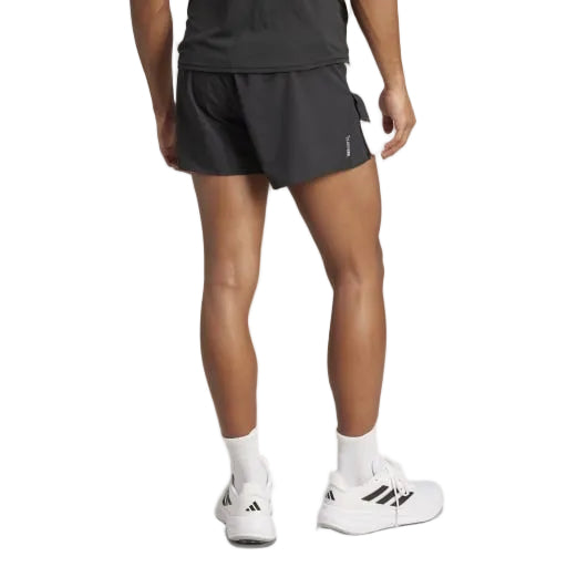 En person iført sort T-shirt, Adidas Adizero Archive Gel Shorts 3" til mænd i sort, hvide strømper og hvide Adidas-sneakers står med ryggen til kameraet mod en ensfarvet baggrund.