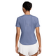 En person står med ryggen til kameraet iført en Nike Dri-FIT kortærmet løbetop til kvinder i World Indigo/Reflective Silver og hvide shorts på en almindelig hvid baggrund.