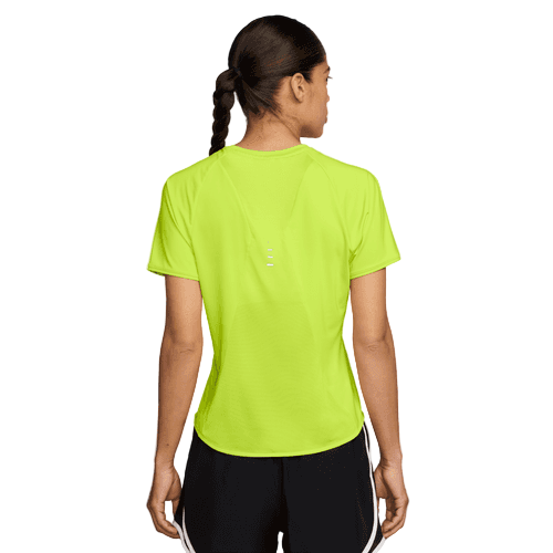 En kvinde med flettet hår kigger væk iført en Nike Swift SS Løbetop til kvinder i Cyber/Reflective Silver og sorte shorts med hvide striber.
